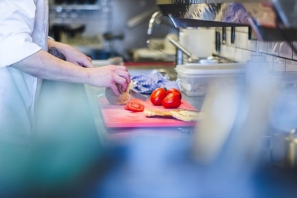 Picture of chef cutting tomatoes in the kitchen. 